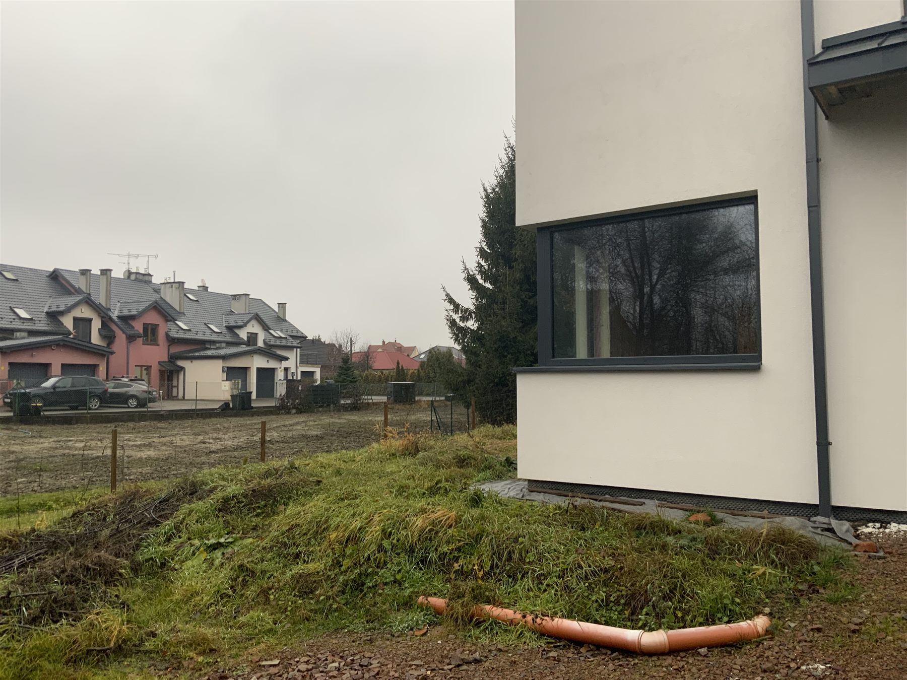 Boczna część domu z dużym oknem i ogrodem